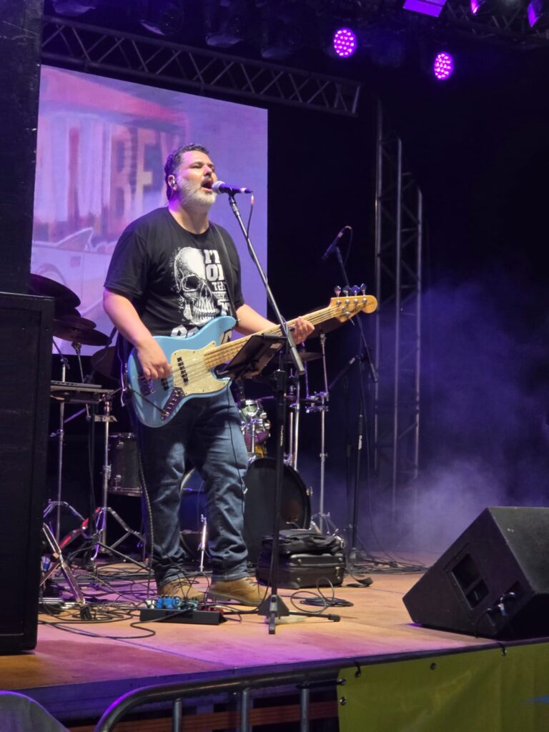 Kalhambex tocando em palco de festival, com painel de LED e iluminacao