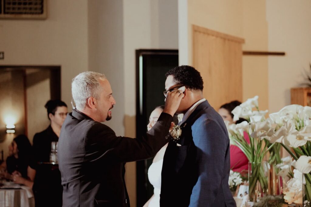 Cerimonialista enxugando o rosto emocionado do noivo durante o casamento