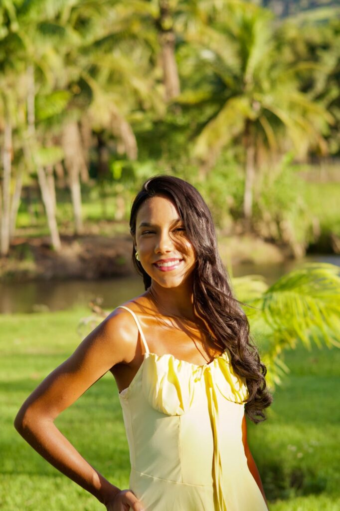 Mulher de vestido amarelo sentada à beira de um lago em ensaio fotográfico externo