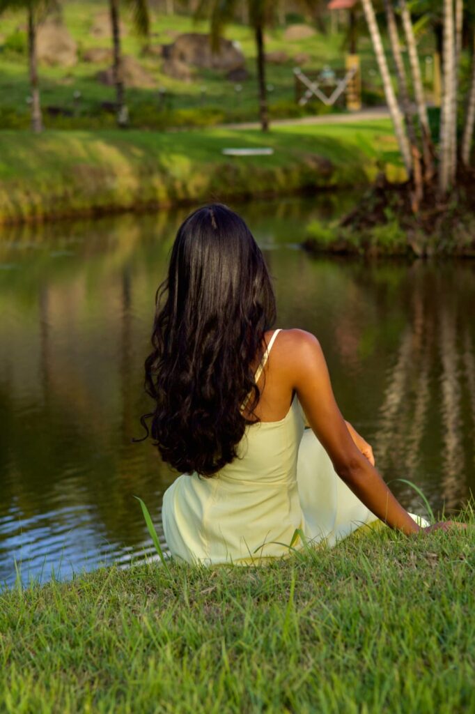 Retrato sorridente de mulher de vestido amarelo em ensaio fotográfico no jardim