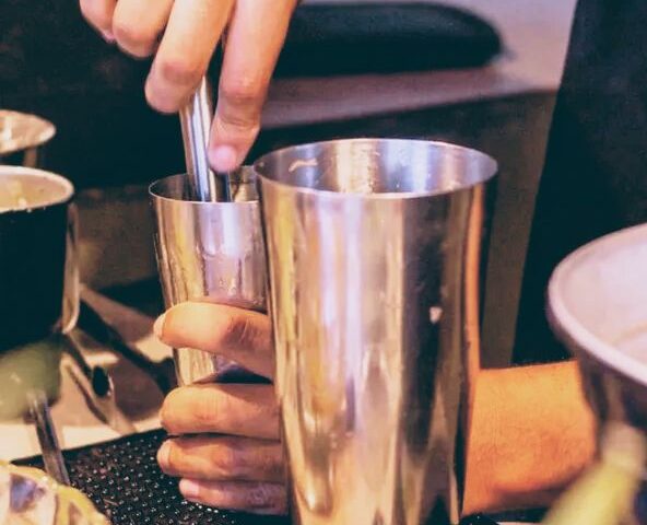 Bartender macerando ingredientes para um drink na coqueteleira, Essencial Drinks RJ